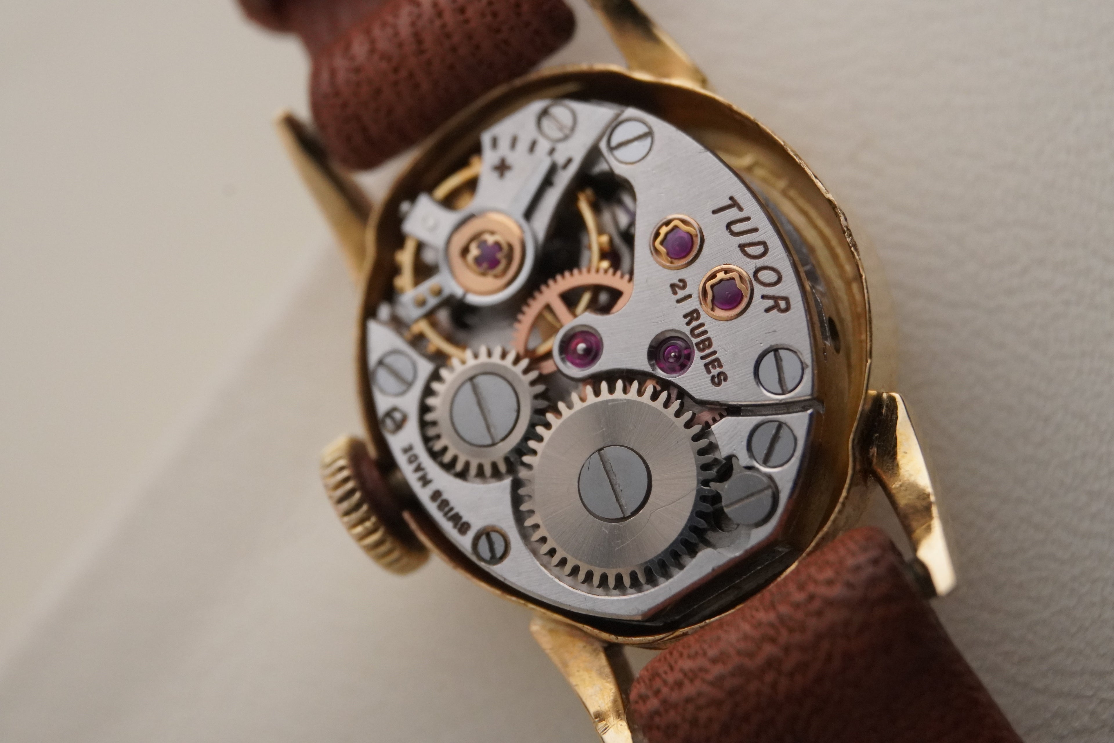 Close-up of a Tudor watch mechanism with visible brand name on a light background