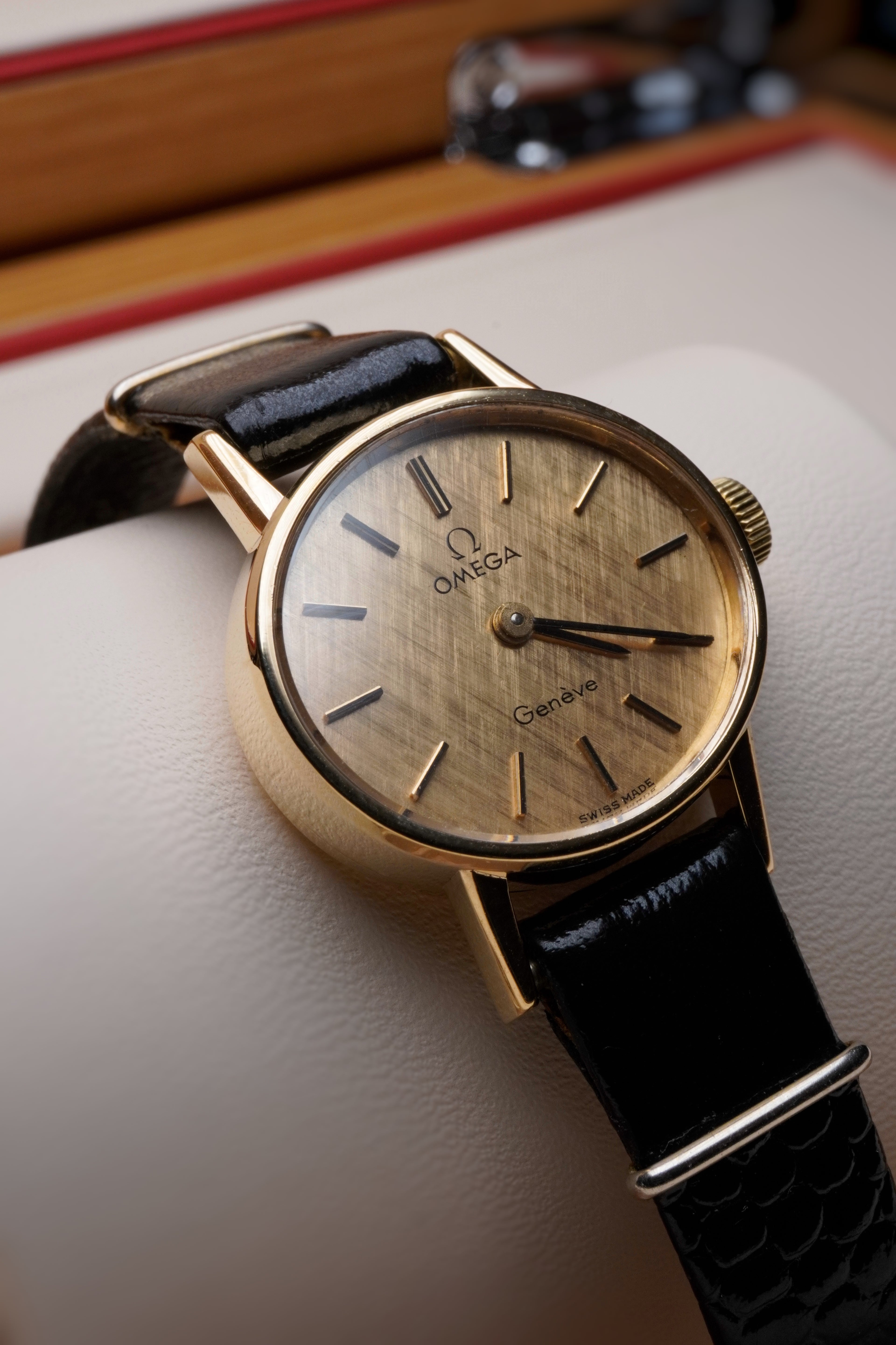 Rare vintage Omega Genève 9ct yellow gold ladies watch with vertical brushed (cadran brossé vertical) dial, gold-tone case, minimalist baton hour markers and black leather strap, Swiss made manual wind dress watch.