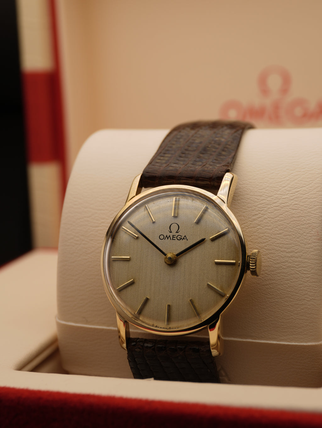 Vintage Omega ladies dress watch with silver dial, applied baton hour markers, 9ct solid gold case and brown leather strap, displayed in original Omega presentation box.