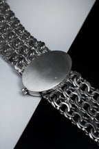 Solid silver ladies Omega De Ville watch with oval case, deep blue textured dial, Roman numerals, and integrated wide silver chain bracelet.