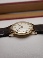 Side of Vintage Omega ladies dress watch with silver dial, applied baton hour markers, 9ct solid gold case and brown leather strap, displayed in original Omega presentation box.