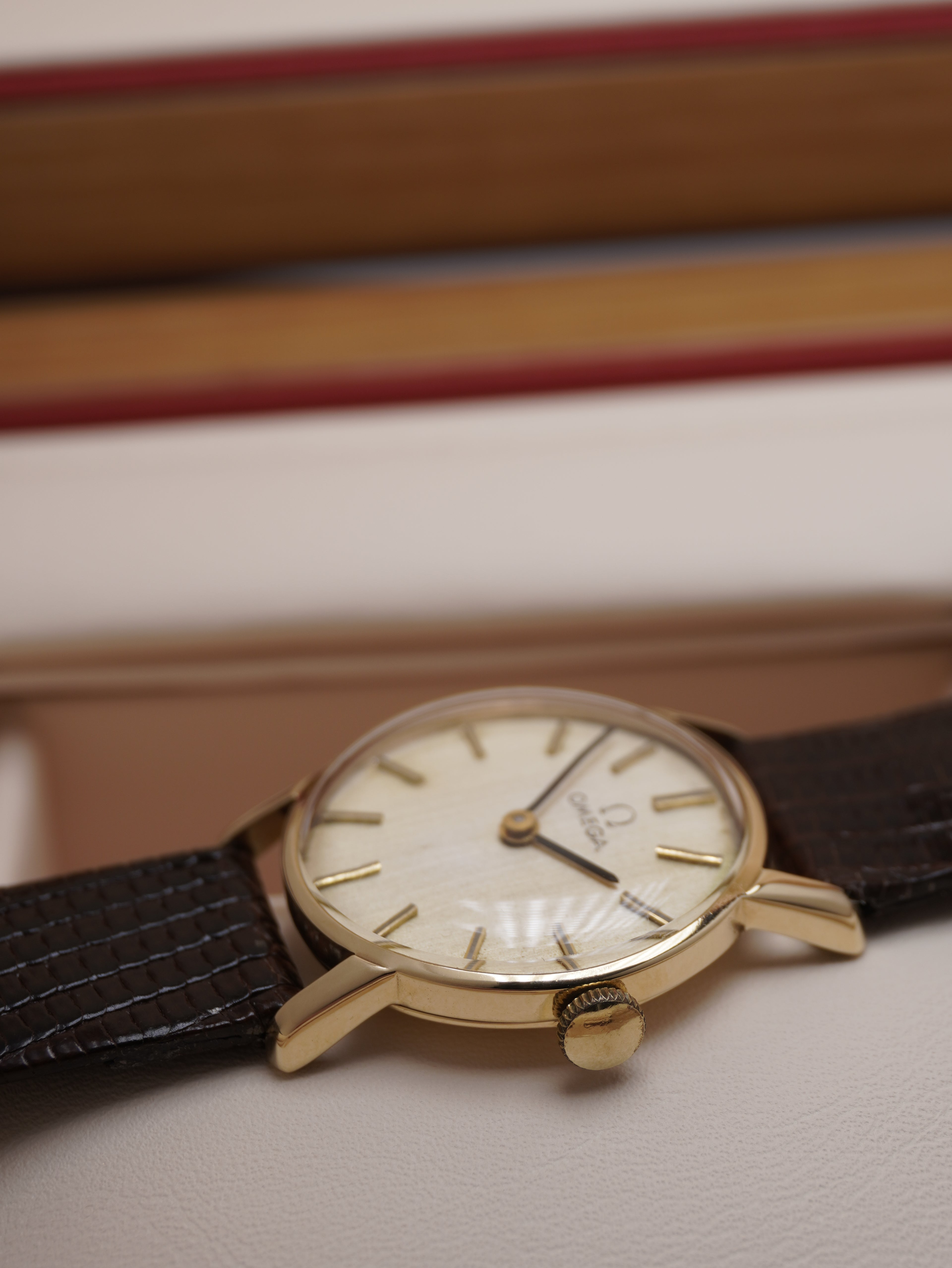 Side view of Vintage Omega ladies dress watch with silver dial, applied baton hour markers, 9ct solid gold case and brown leather strap, displayed in original Omega presentation box.