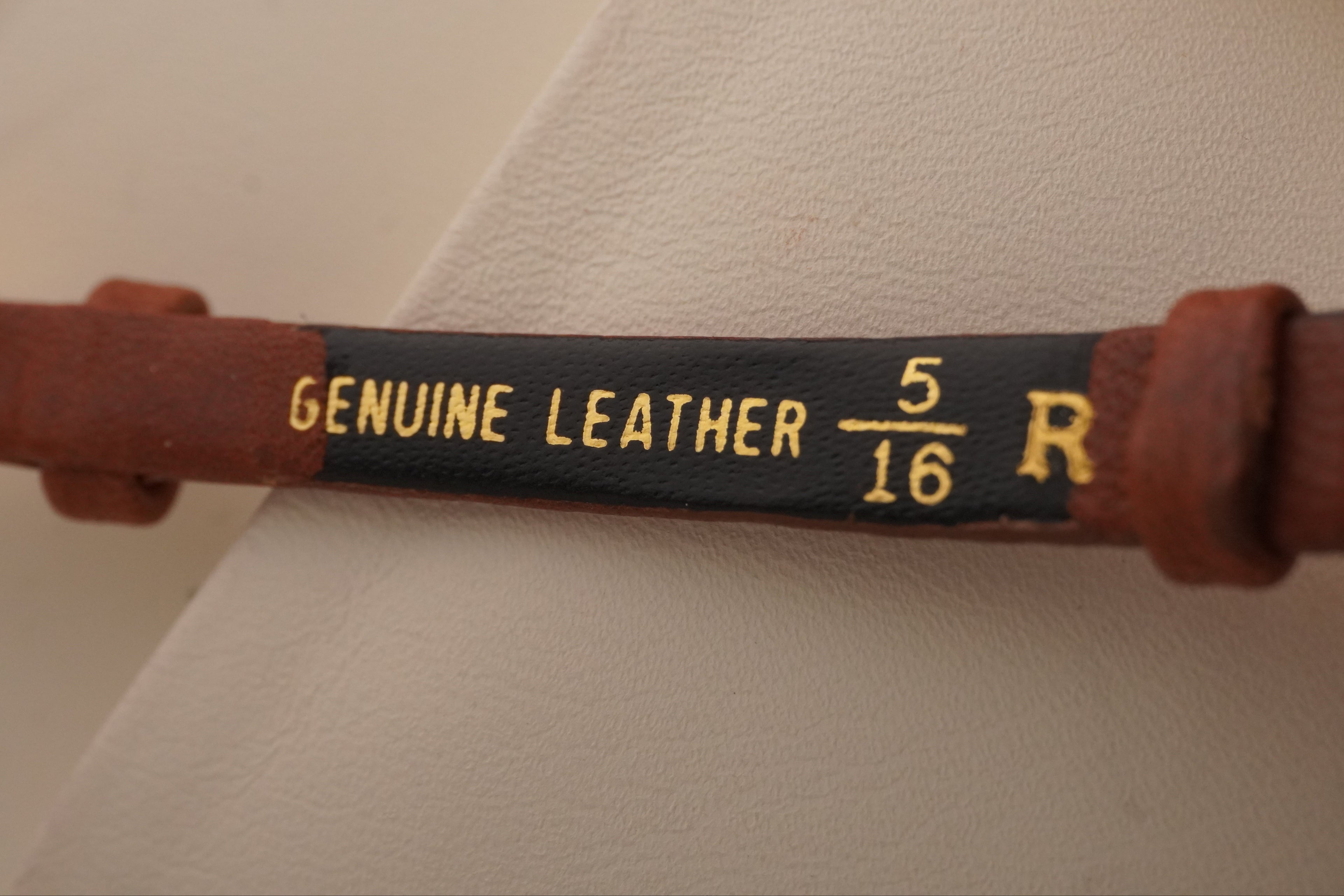 Brown leather belt with 'Genuine Leather' label on a white background