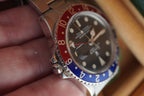 Close-up of a watch with a red and blue bezel held by a hand. Rolex 1675 GMT master