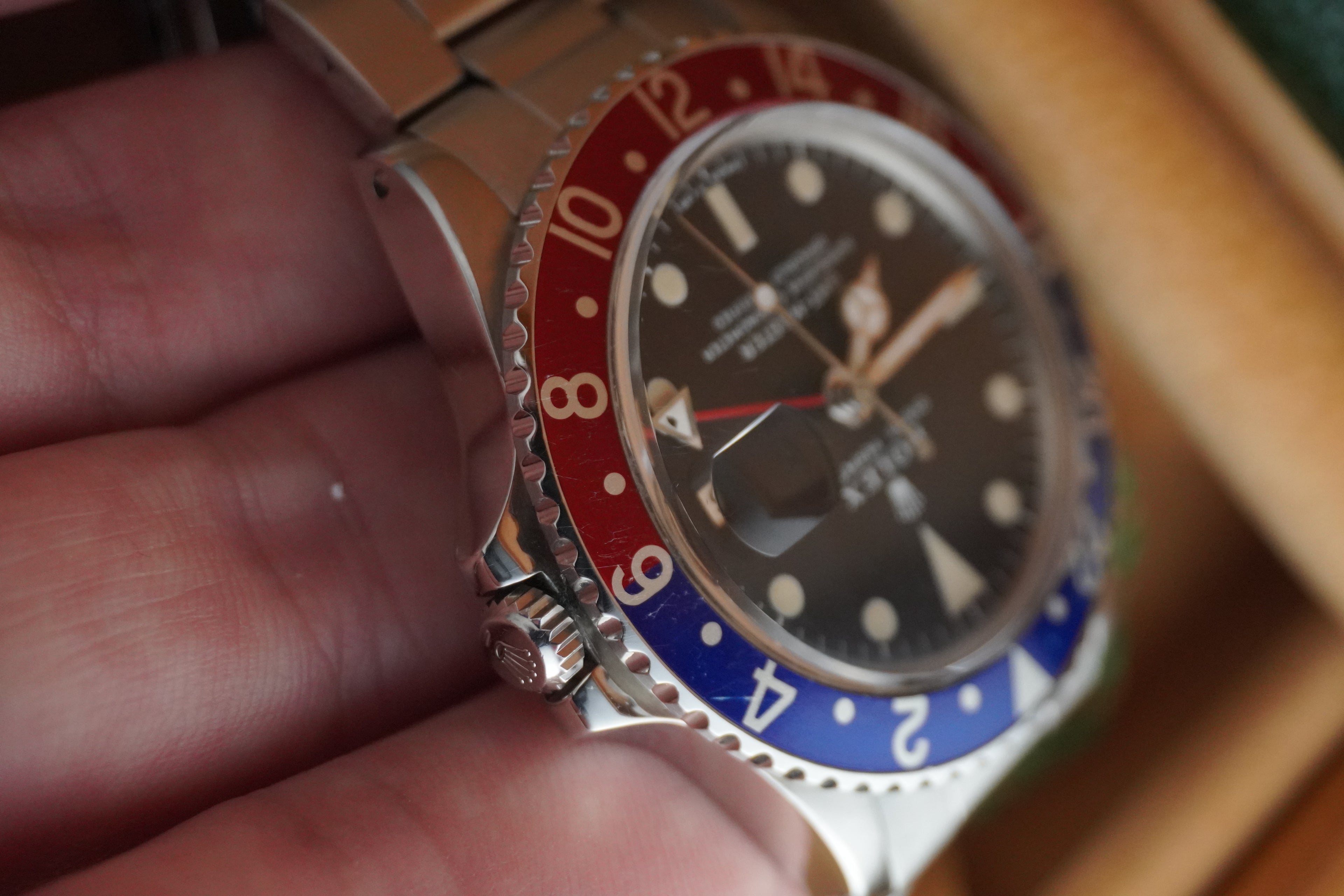 Close-up of a watch with a red and blue bezel held by a hand. Rolex 1675 GMT master