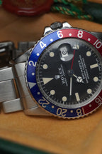 Vintage Rolex GMT-Master Pepsi bezel stainless steel watch with red and blue bezel insert, black dial, and Oyster bracelet displayed in original presentation box with Swiss chronometer seal.