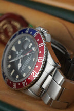 Vintage Rolex GMT-Master Pepsi bezel stainless steel watch with red and blue bezel insert, black dial, and Oyster bracelet displayed in original presentation box with Swiss chronometer seal.