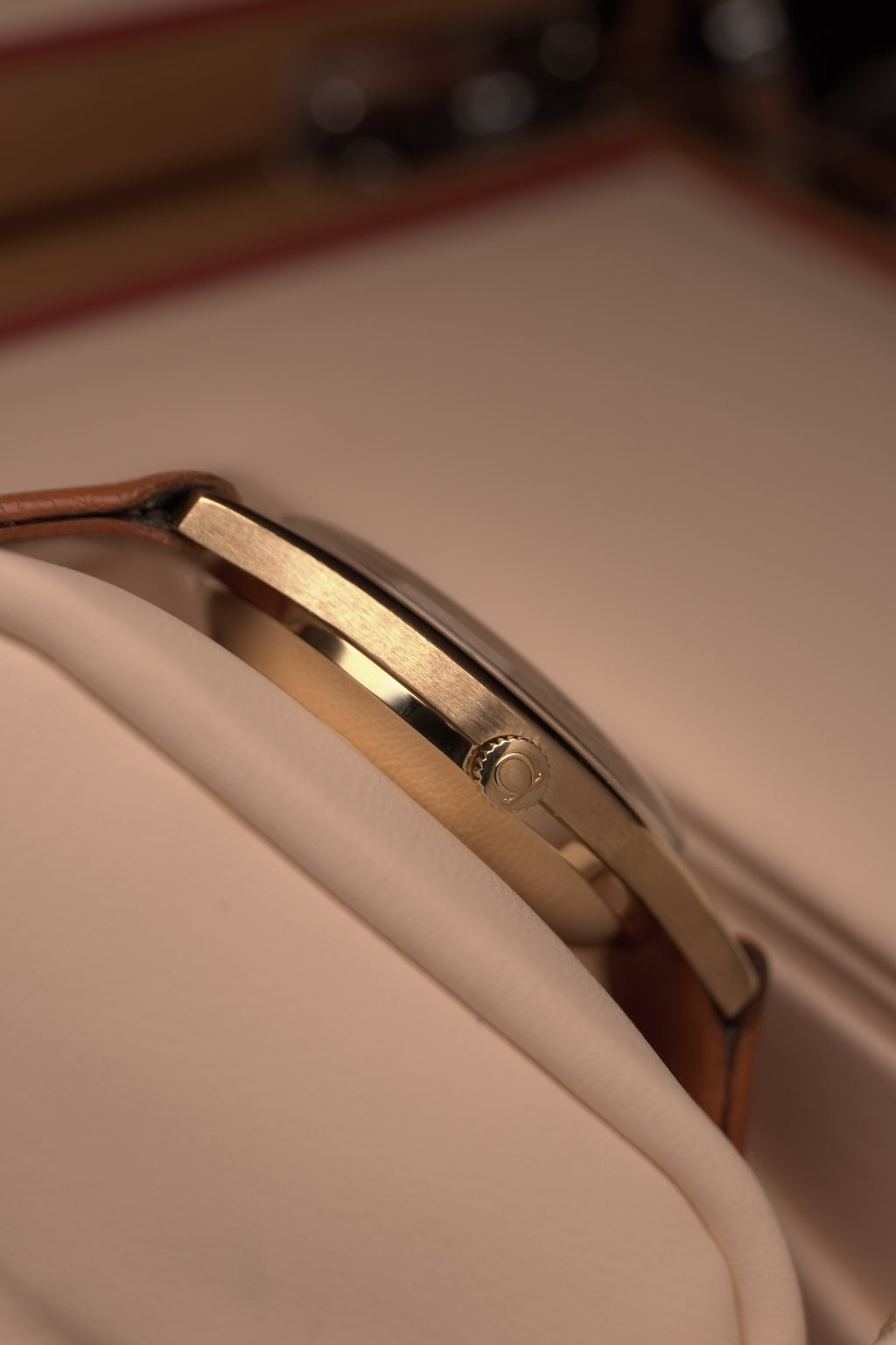 Side profile Angled close-up of a vintage Omega Automatic gents watch in solid yellow gold with a champagne dial, baton hour markers and date window, on a brown leather strap.