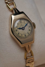 Close-up images of an early 1950s ladies’ Omega wristwatch with a 9ct gold Dennison case, cream dial with Arabic numerals, blued steel hands, inner caseback hallmarkings, and a side profile of the watch.