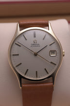 Front-on view of a vintage 1974 Omega 9 ct yellow-gold dress watch (Ref. 162.5422), showing a champagne-coloured dial with applied gold hour markers, black pencil-style hands, a date window at 3 o’clock, and a polished gold bezel.