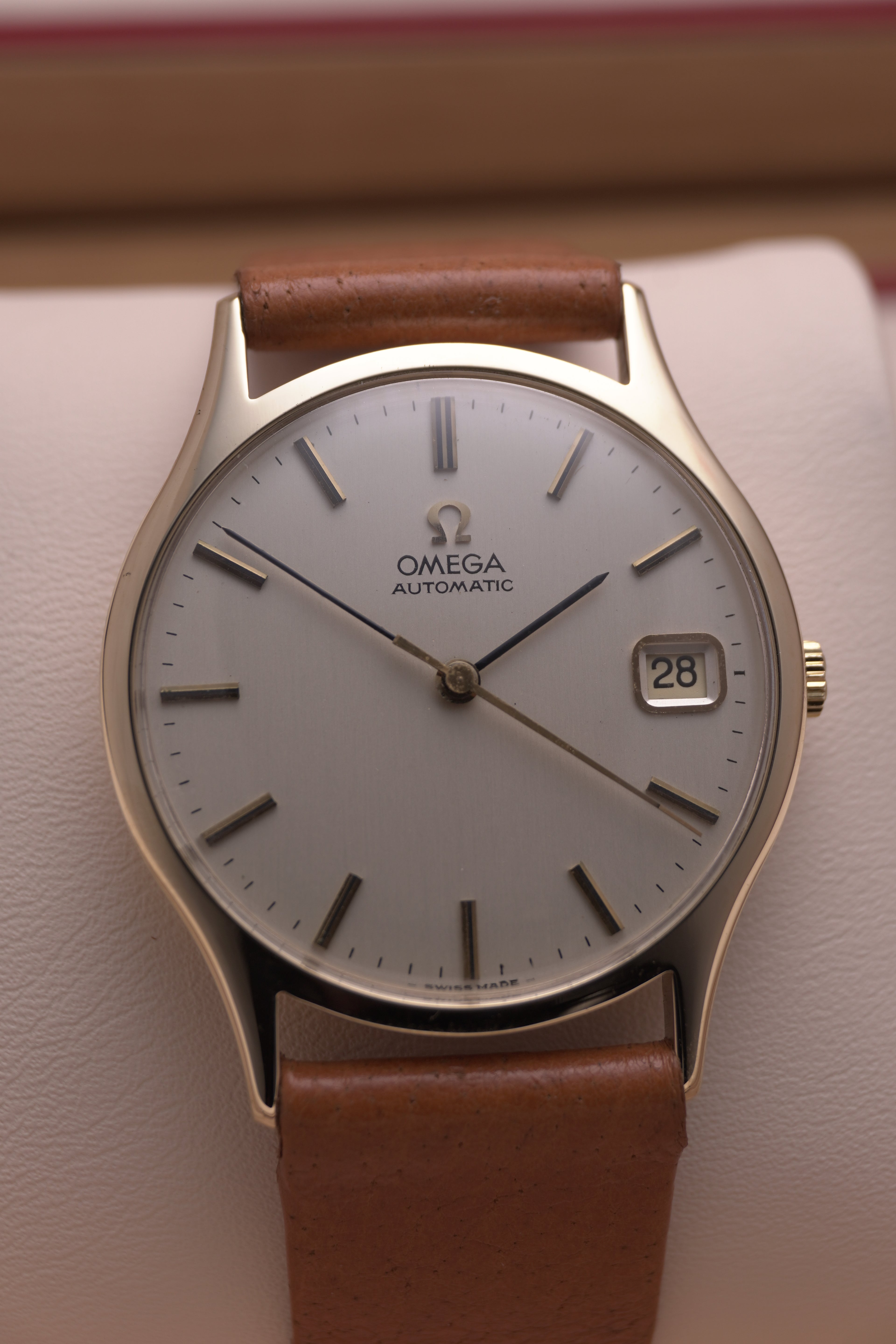 Front-on view of a vintage 1974 Omega 9 ct yellow-gold dress watch (Ref. 162.5422), showing a champagne-coloured dial with applied gold hour markers, black pencil-style hands, a date window at 3 o’clock, and a polished gold bezel.